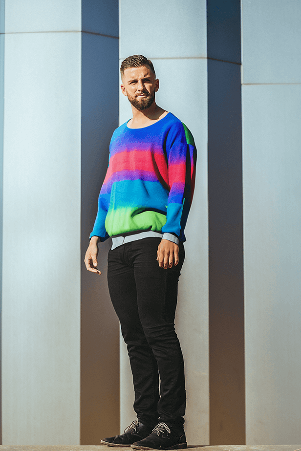 Male model standing slightly turn wearing neon coloured sweater